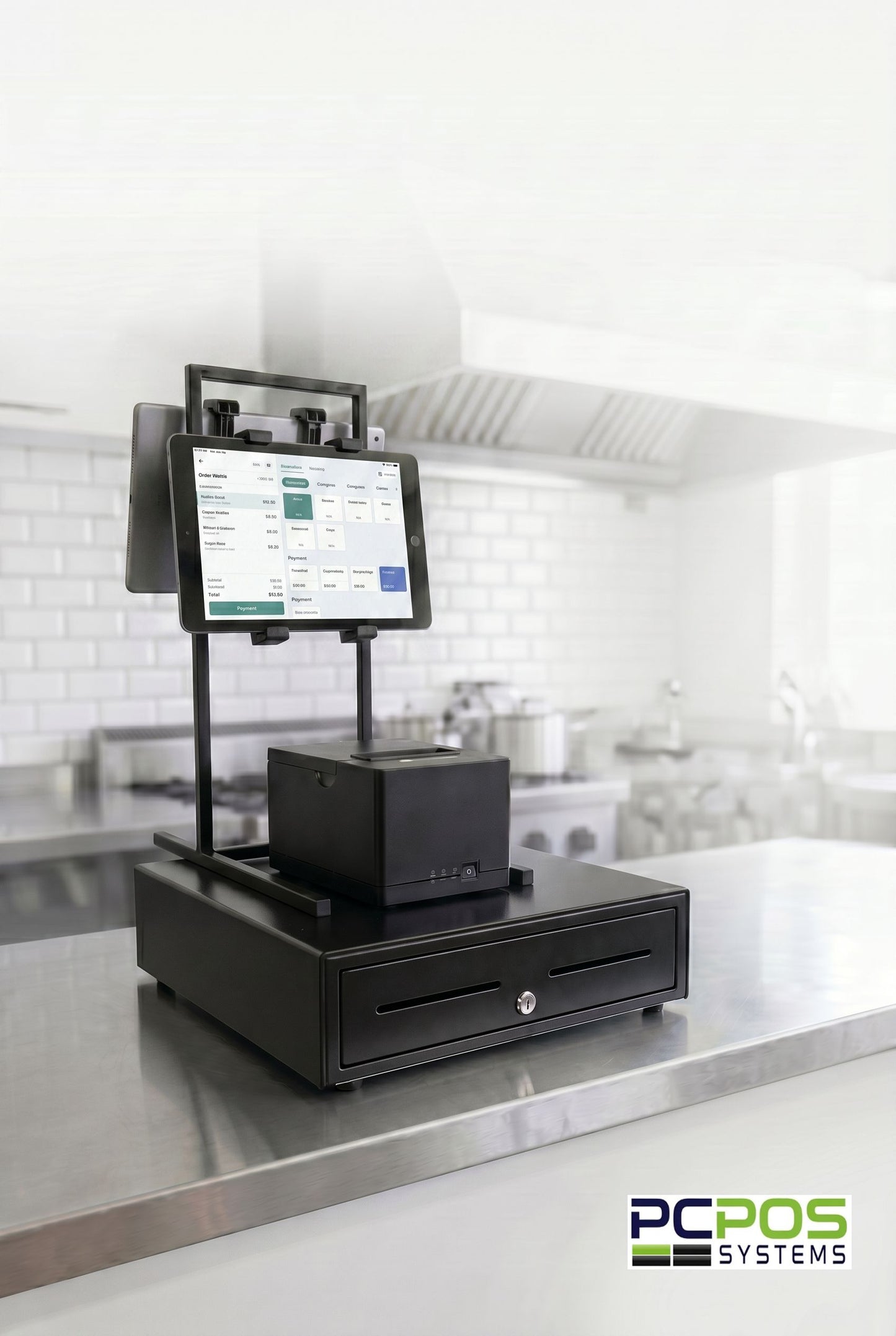 A Heavy-duty PCPOS Tablet Tower by PCPOS Systems, holding up to 3 tablets (7–10”) for DoorDash, Uber Eats, and POS, is on a stainless steel counter in a commercial kitchen with the PCPOS Systems logo in the bottom right corner.