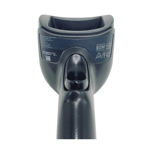 Close-up of the bottom view of a black PCPOS Systems Honeywell Xenon 1950 1D/2D Scanner (RS232, 1950GSR-2-R) showing certification labels and symbols, including NOM, CE, and FCC.
