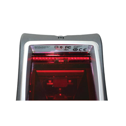 Close-up of a PCPOS Systems Honeywell Genesis 7580 barcode scanner with red light in the scanning window and certification labels on top. This desktop scanner connects via USB for fast, efficient checkout.