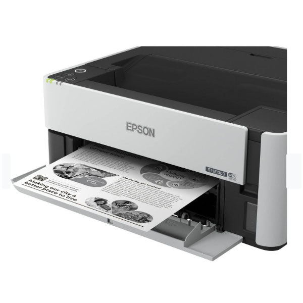 The PCPOS Systems Epson WorkForce ST-M1000 printer is shown in use, delivering a sharp black-and-white document. This sleek monochrome inkjet model features top-left buttons for easy cartridge-free printing and achieves 1200 x 2400 dpi precision with text and grayscale images.