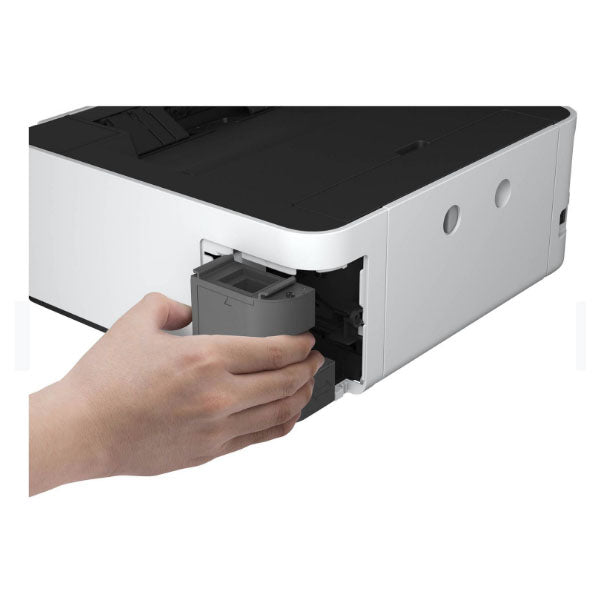 A hand removes a toner cartridge from the compact, white PCPOS Systems Epson WorkForce ST-M1000 Desktop Inkjet Printer featuring PrecisionCore technology. The front panel is open, displaying the cartridge compartment of this sleek, monochrome printer with a 1200 x 2400 dpi print resolution.